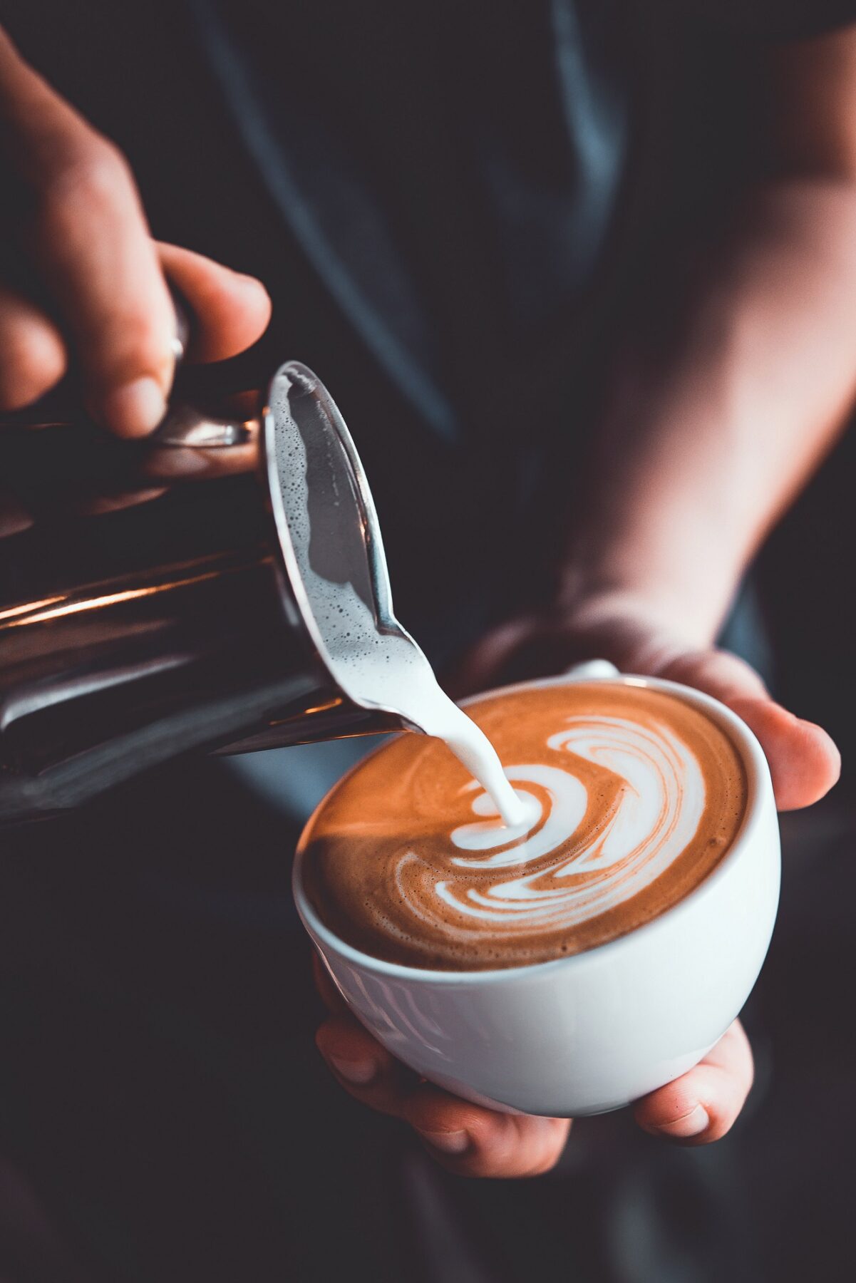 Barista pouring a latte up close