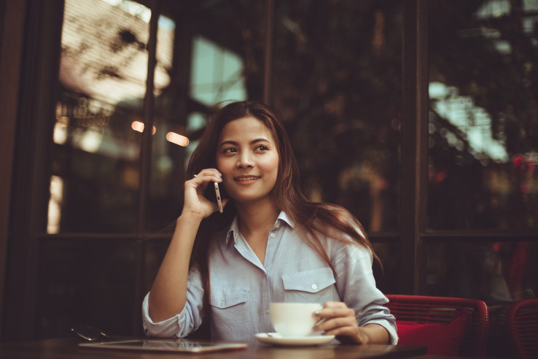 Woman sitting outside of a cafe talking on a cell phone
