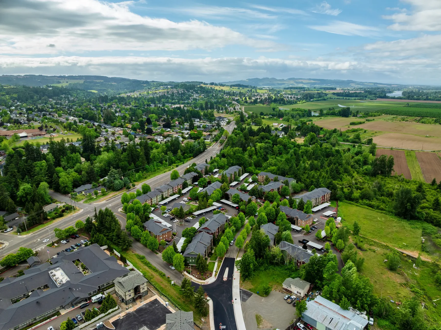 Aerial view of Willamette Park apartments with green fields on the right and clustered houses on the left.