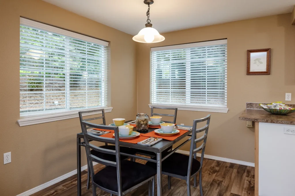Dining area with a rectangular table set for four, colorful tableware on an orange runner.