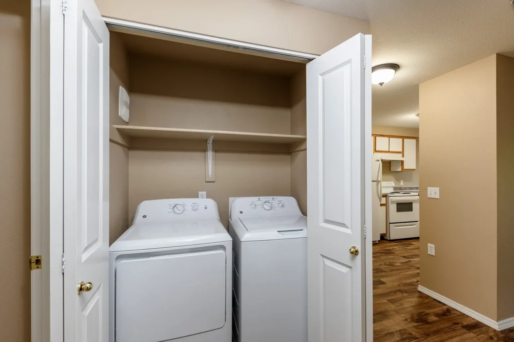 Washer and dryer machine in closet with view of kitchen space.