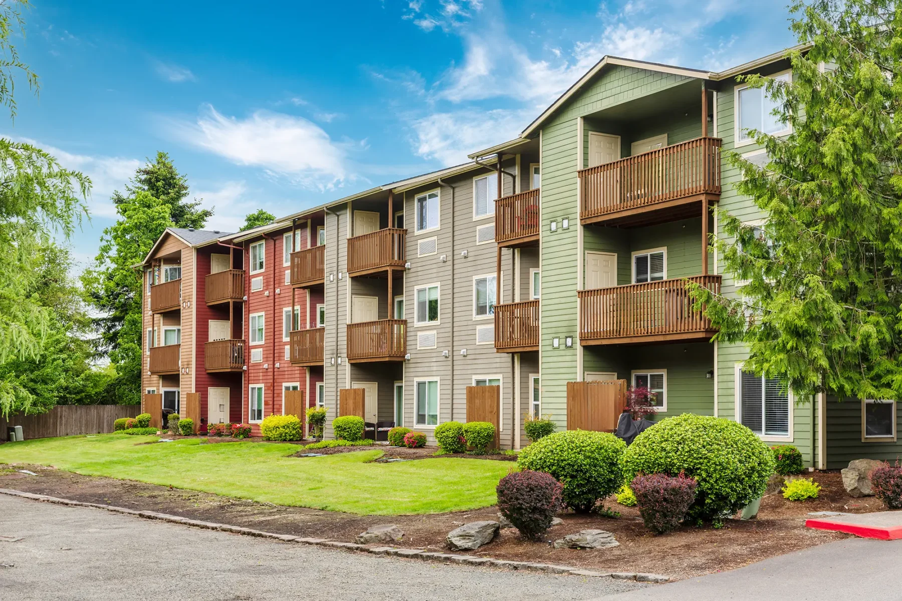 Three story apartment buildings with fenced in balconies and green, beige and red exteriors.